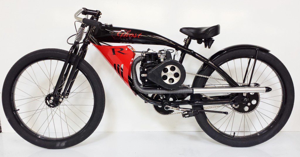 A black and red bike is parked against a white wall.