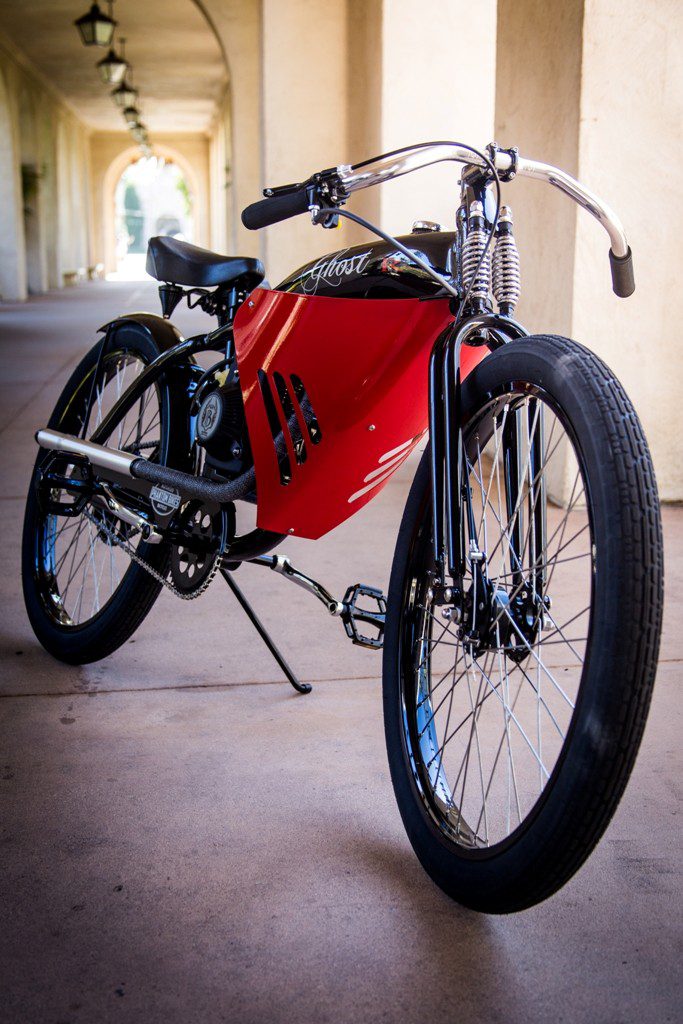 A red and black motorcycle parked under a bridge.