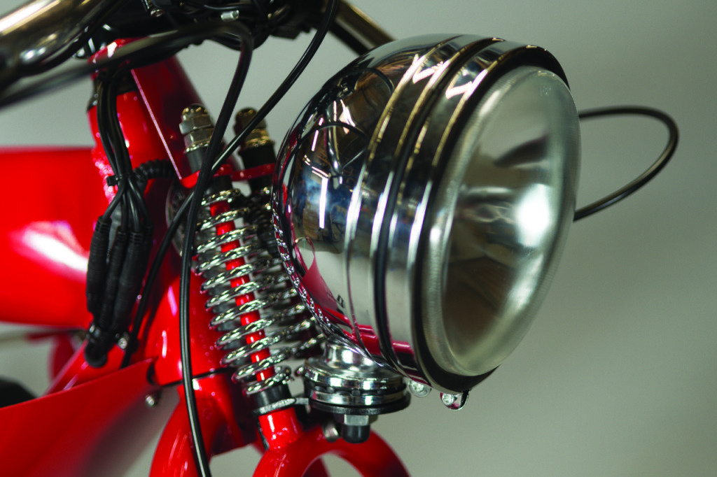 A close up of the headlight of a red bike.