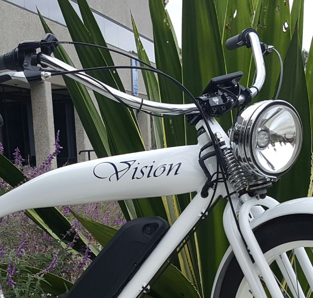 A white electric bike parked in front of some plants.